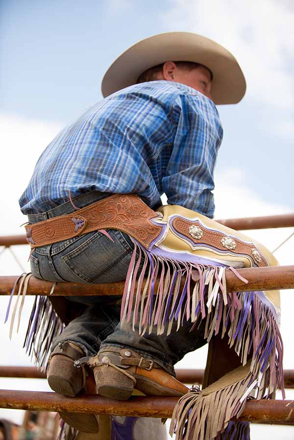 Cowboy sitting on a fence..